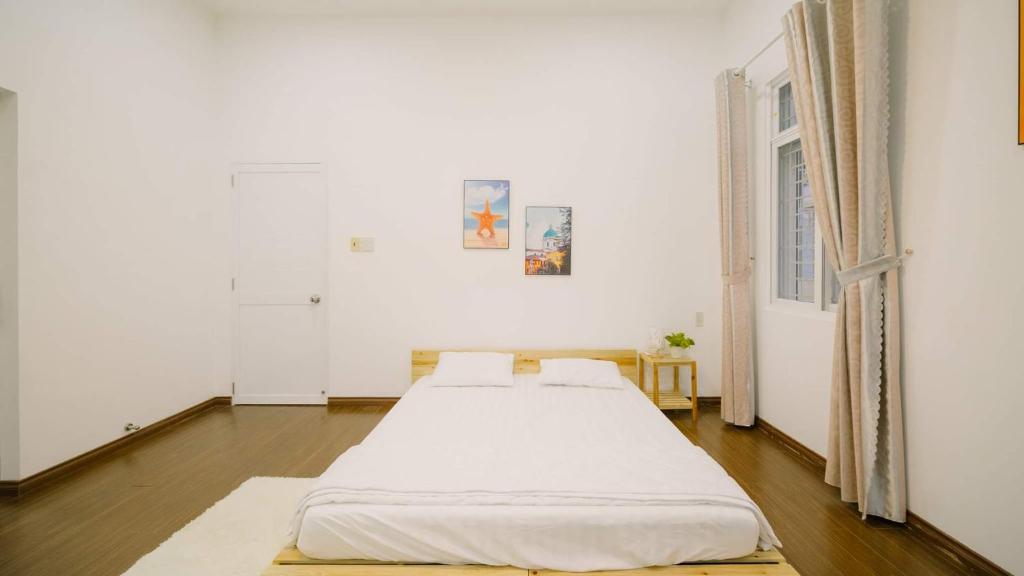 two beds in a white room with a window at Nha Trang Riverside Villa in Nha Trang