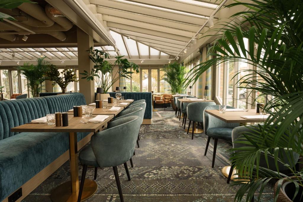 un restaurant avec des tables, des chaises et des plantes dans l'établissement Carlton Oasis Hotel, à Spijkenisse