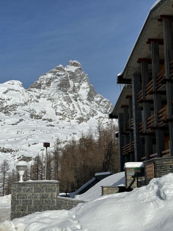 une montagne enneigée devant un bâtiment dans l'établissement Maison Rododendro Elegant, à Breuil-Cervinia