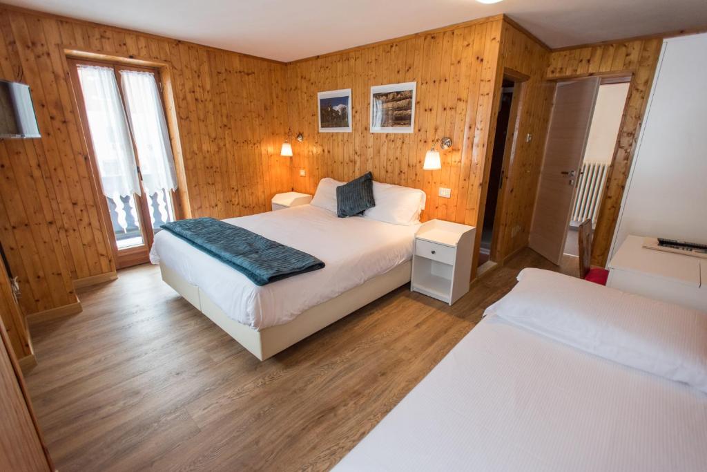 a bedroom with a bed and two windows and wooden walls at Hotel Signal in Macugnaga