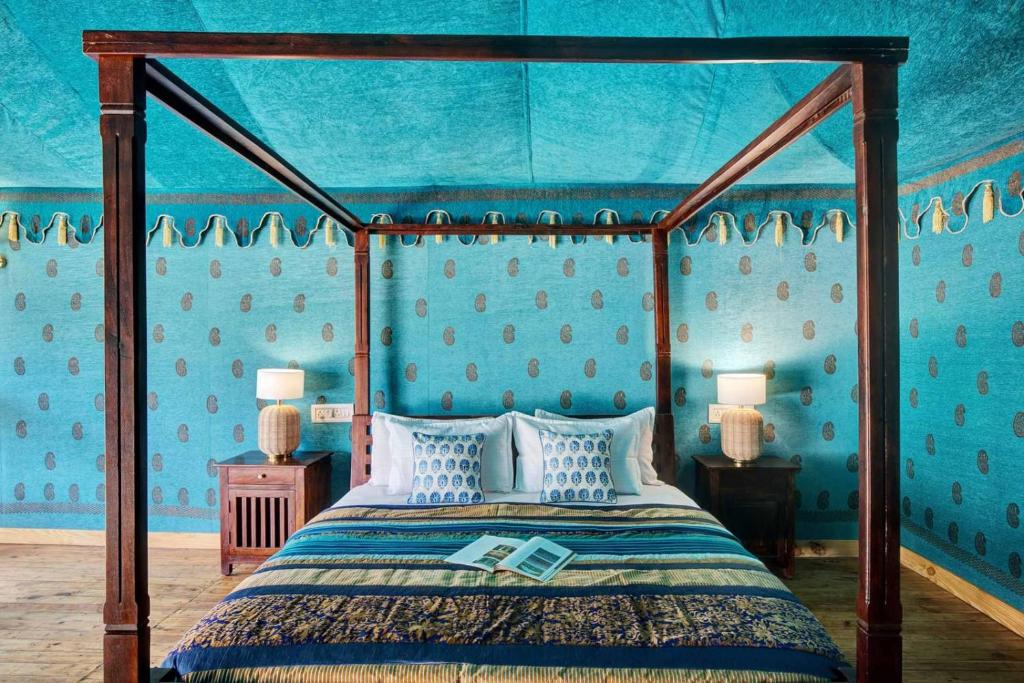 a bedroom with a canopy bed with blue walls at Foothill Pushkar Resort in Pushkar