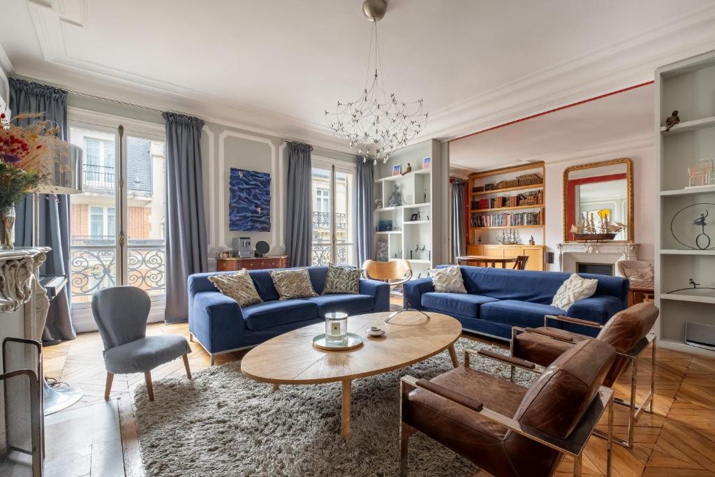 un salon avec un canapé bleu et une table dans l'établissement Veeve - The Artist's Residence, à Paris