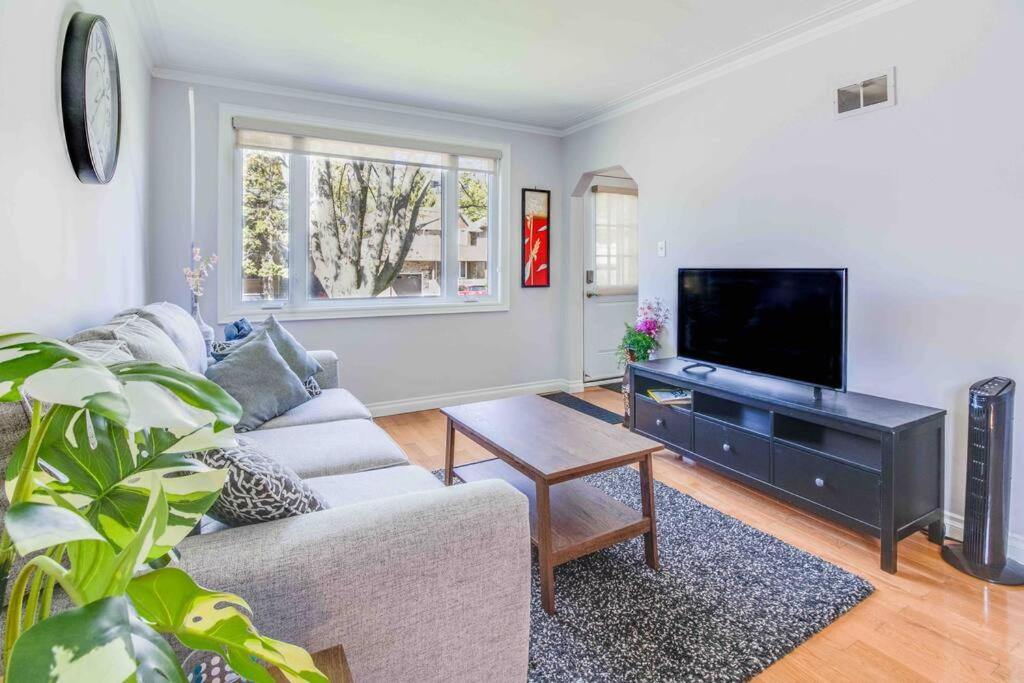 a living room with a couch and a flat screen tv at Beautiful house near bluffers beach, 25 minutes to Toronto Downtown, free parking, and wifi in Toronto