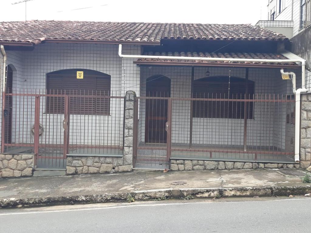a building with two doors and a fence at Quartos em casa no Clelia Bernardes in Viçosa