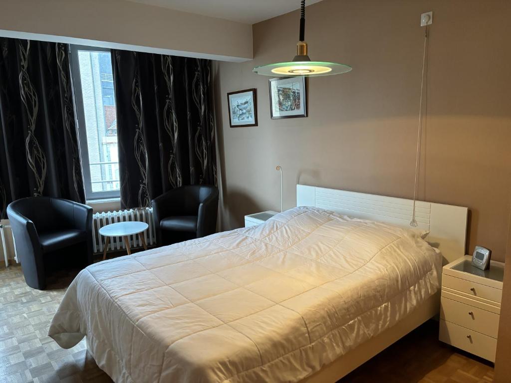 1 Schlafzimmer mit einem Bett, 2 Stühlen und einem Fenster in der Unterkunft Zilverzee 0301 in Koksijde