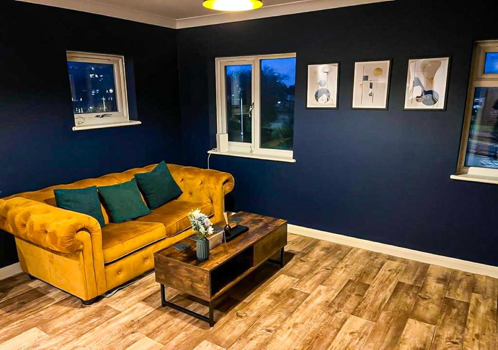 sala de estar con sofá amarillo y paredes azules en Chic Coastal Hideaway: 2-BR Gem Southend Stays, en Southend-on-Sea