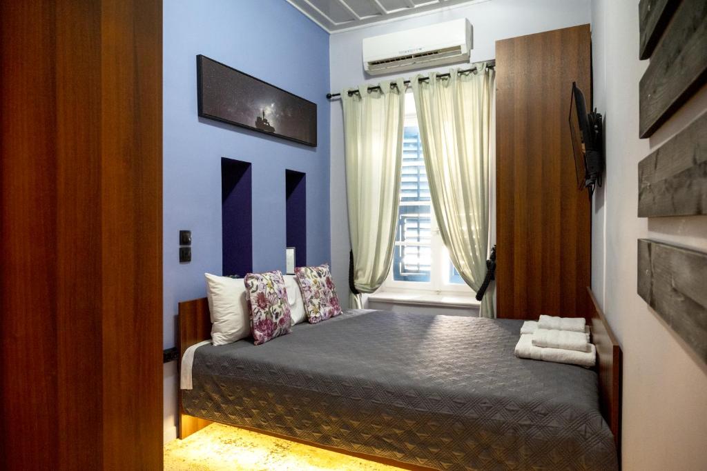 una camera da letto con un letto con pareti blu e una finestra di Deisisroom nafplio Afroditi a Nauplia