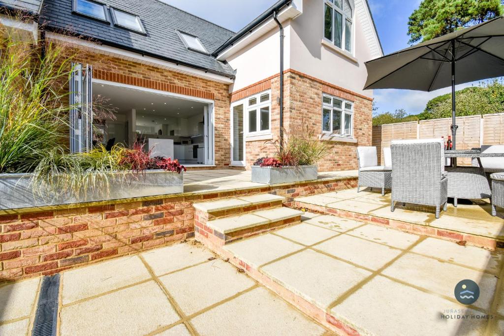 a patio with a table and chairs and an umbrella at Days Away - Luxury holiday home in Radipole
