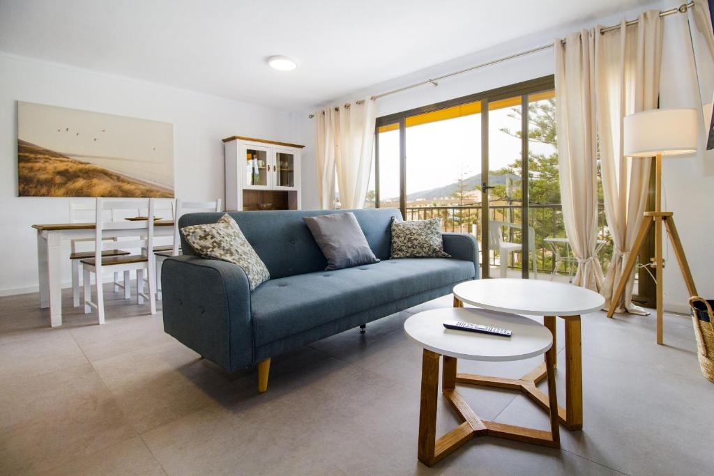 ein Wohnzimmer mit einem blauen Sofa und einem Tisch in der Unterkunft Apartamento Ponent 2 in Cala Ratjada