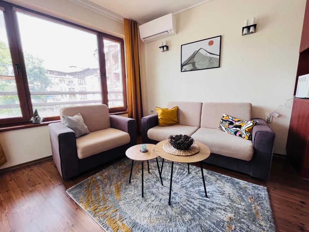 a living room with two couches and a table at Mountain Cedar Pine 1 BR Apt near Ski Gondola in Bansko