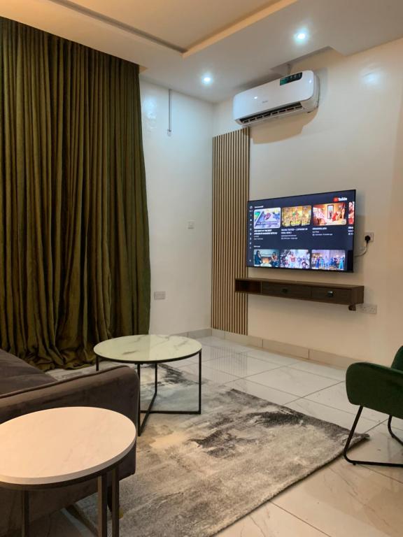 ein Wohnzimmer mit 2 Tischen und einem Flachbild-TV in der Unterkunft Luxury apartments in Ibadan