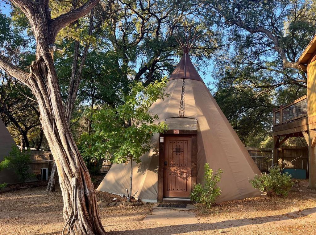 ein Tipi-Zelt mit einer Tür neben einem Baum in der Unterkunft Deer Run - Tipi 2 in New Braunfels