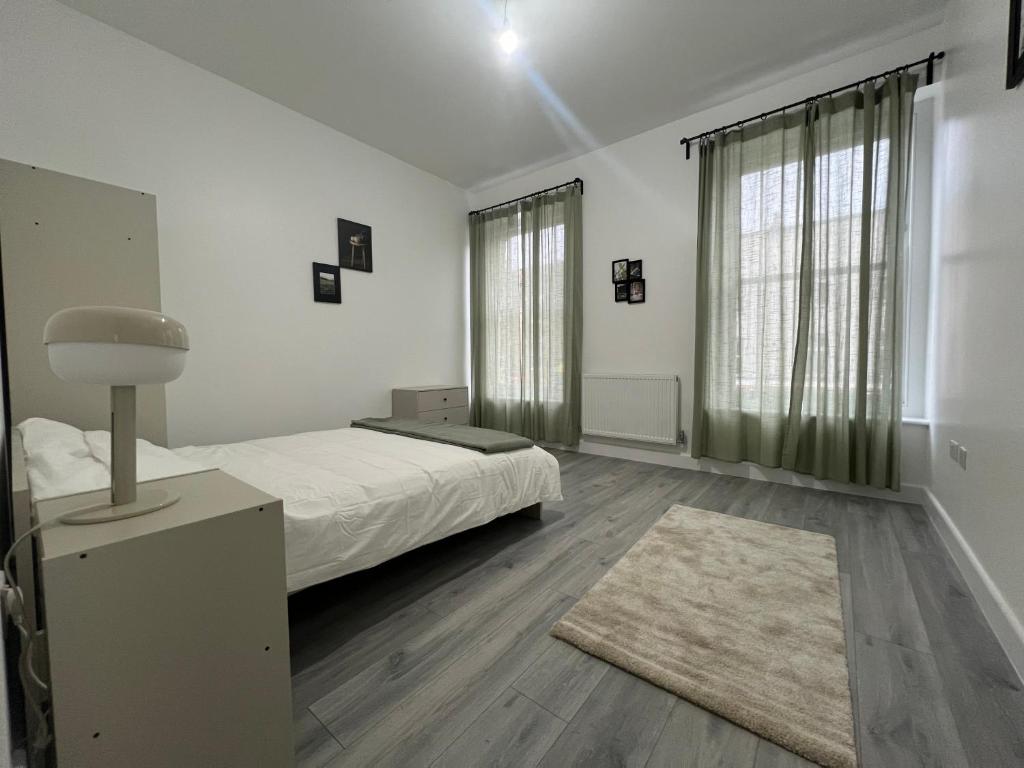 a white bedroom with a bed and a rug at London Homes in London