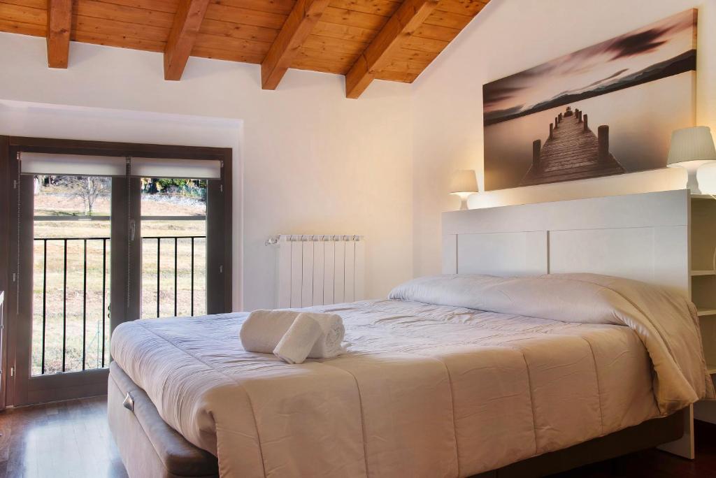 - une chambre avec un grand lit blanc et un balcon dans l'établissement Relax Tra Monti e Laghi, à Brenta
