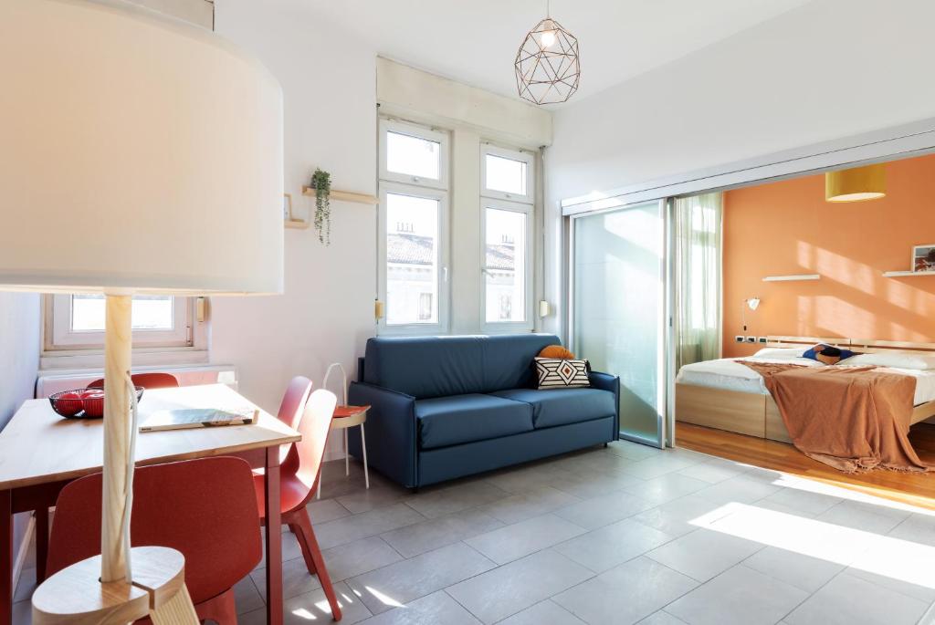 ein Wohnzimmer mit einem blauen Sofa und ein Schlafzimmer in der Unterkunft ALTIDO Trendy units in the city centre in Triest