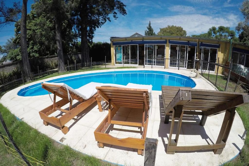 a pool with two wooden tables and chairs next to it at Quinta el Olivo con piscina en Buenos Aires in Alejandro Korn