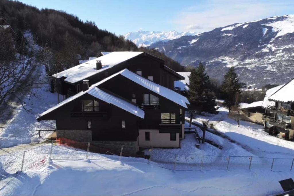 a house covered in snow with mountains in the background at Charming Apt With Balcony In La Plagne Montalbert in La Plagne