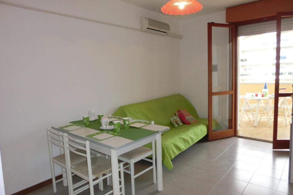 ein Esszimmer mit einem Tisch und einem grünen Sofa in der Unterkunft Modern 1 bedroom apartment with balcony - Beahost in Bibione