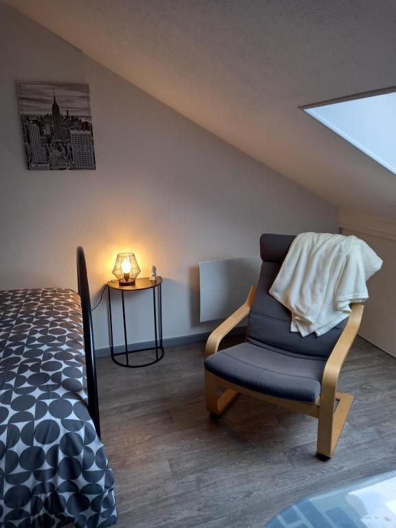 a attic room with a bed and a chair at Studio tout équipé in Revigny-sur-Ornain
