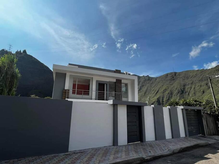 a white house with a fence in front of a mountain at Moderna casa vacacional en Baños in Juivi