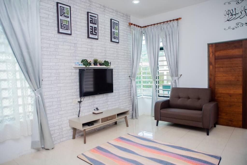 CikJah Guest House SEMI-D في كُوانتان: غرفة معيشة مع أريكة وتلفزيون وكرسي