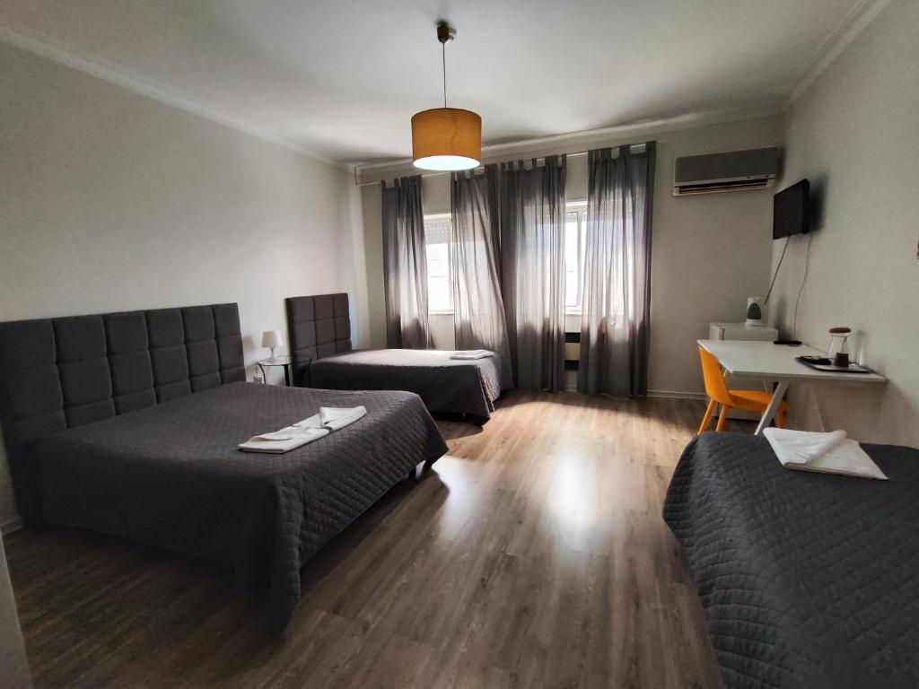 a room with two beds and a table and a desk at Residencial Centro Comercial Avenida Bragashopping in Braga