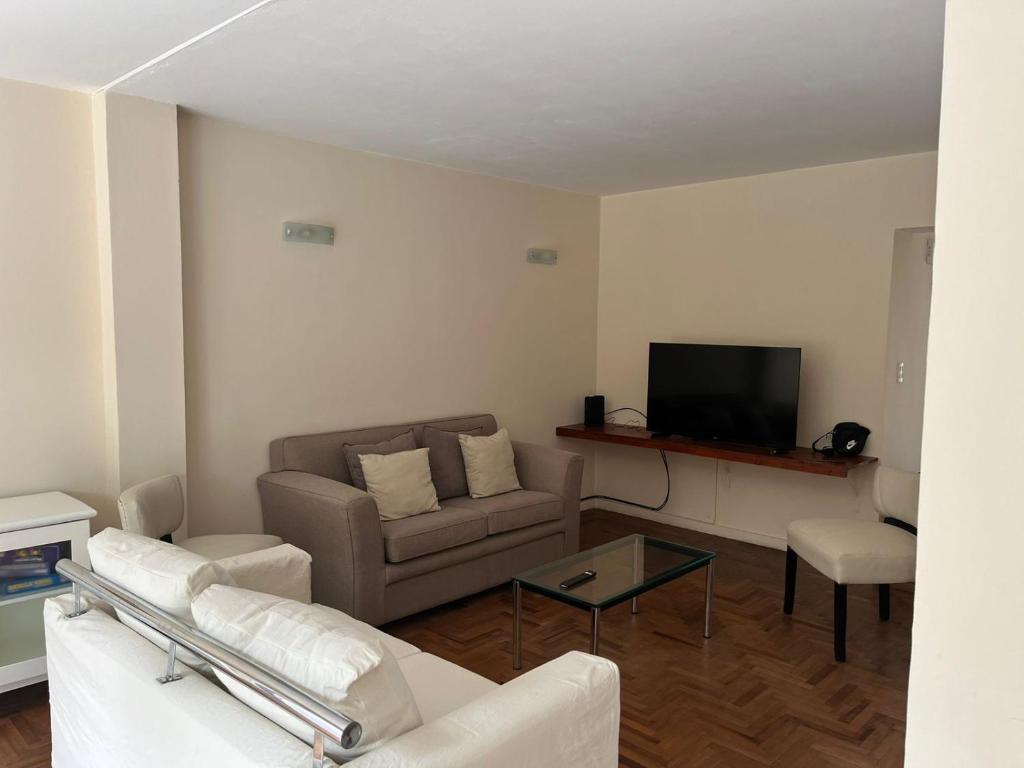 ein Wohnzimmer mit einem Sofa und einem TV in der Unterkunft Casa Cerro de las Rosas in Cordoba