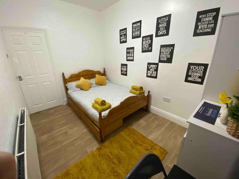 een slaapkamer met een bed met gele kussens en foto's aan de muur bij East Stay 2/3 bedroom Flat in Westoe