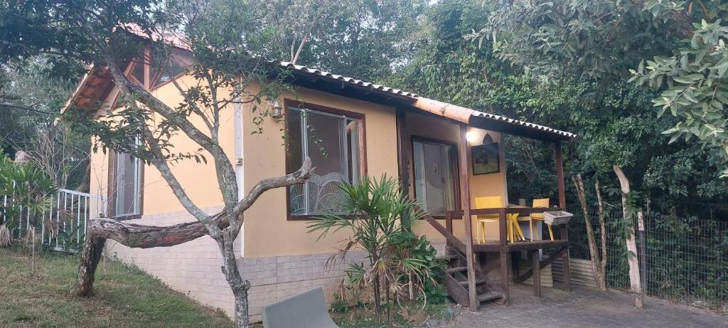 a small yellow house with a table in front of it at CHALÉ Pedaço do Coqueiro in Anchieta