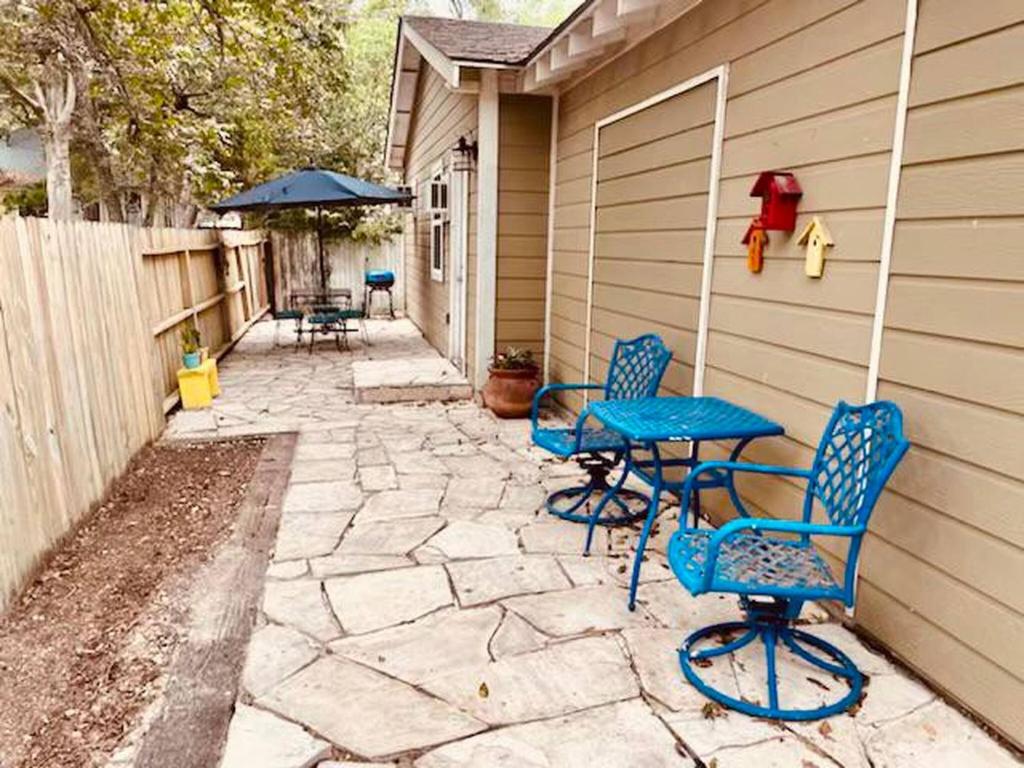 a patio with blue chairs and a table and an umbrella at Elm Street Cottage in Seguin