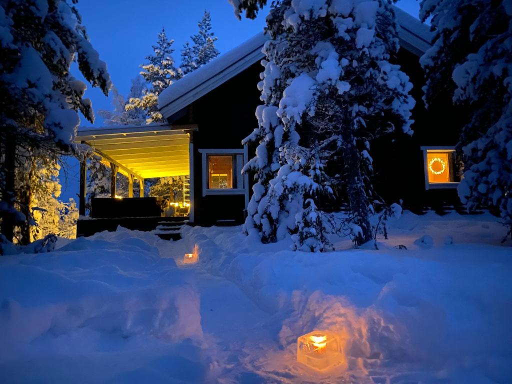 a house in the snow at night at Northern Light Villa Ylläs with a Jacuzzi in Ylläsjärvi