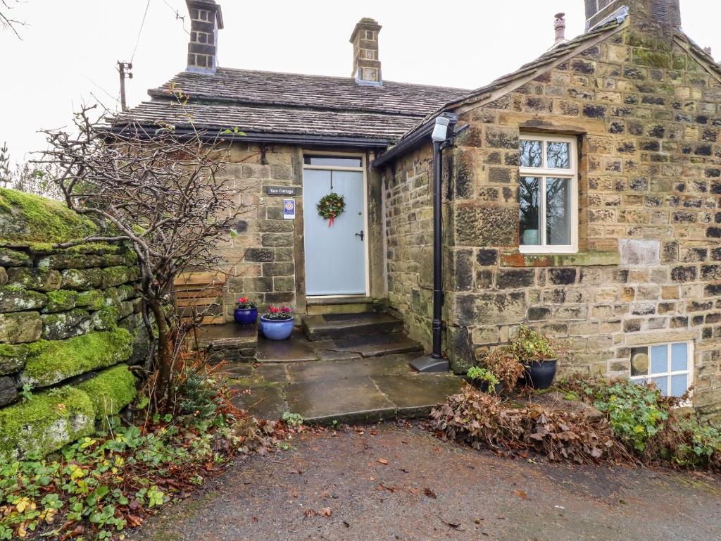 an old stone house with a white door at Yate Cottage in Oxenhope