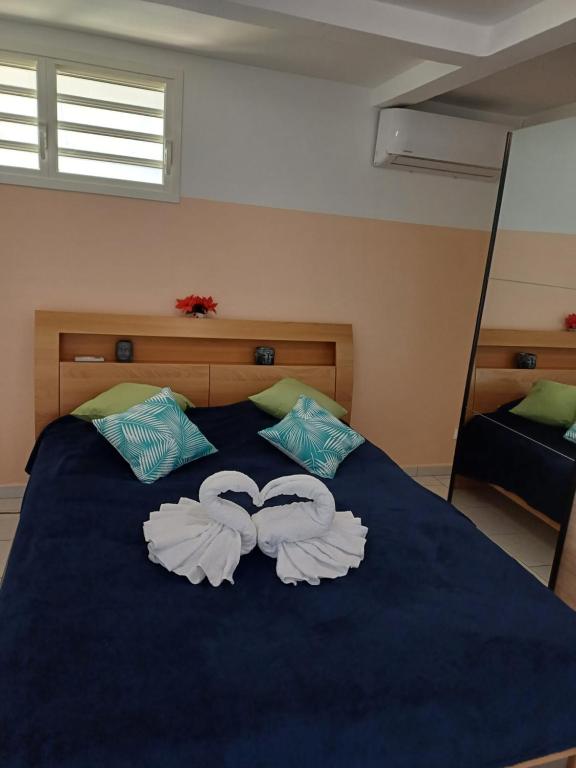 ein blaues Bett mit zwei Handtüchern in Herzform in der Unterkunft Le Cocon de l'Oranger in Le Moule