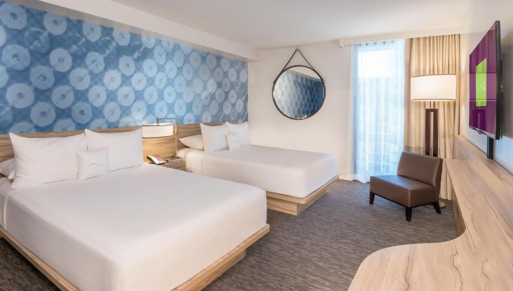 a hotel room with two beds and a chair at The LINQ Hotel and Casino in Las Vegas
