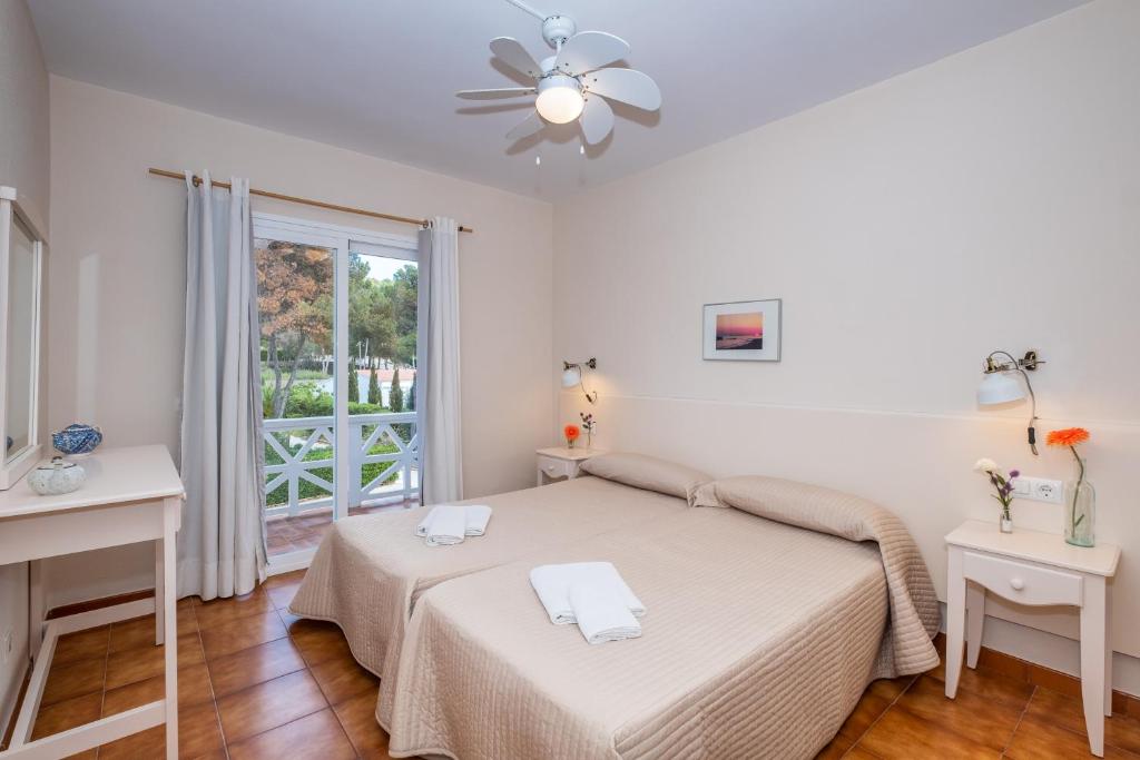 a white bedroom with a bed and a window at apartamento edificio migjorn santo tomas in Santo Tomás