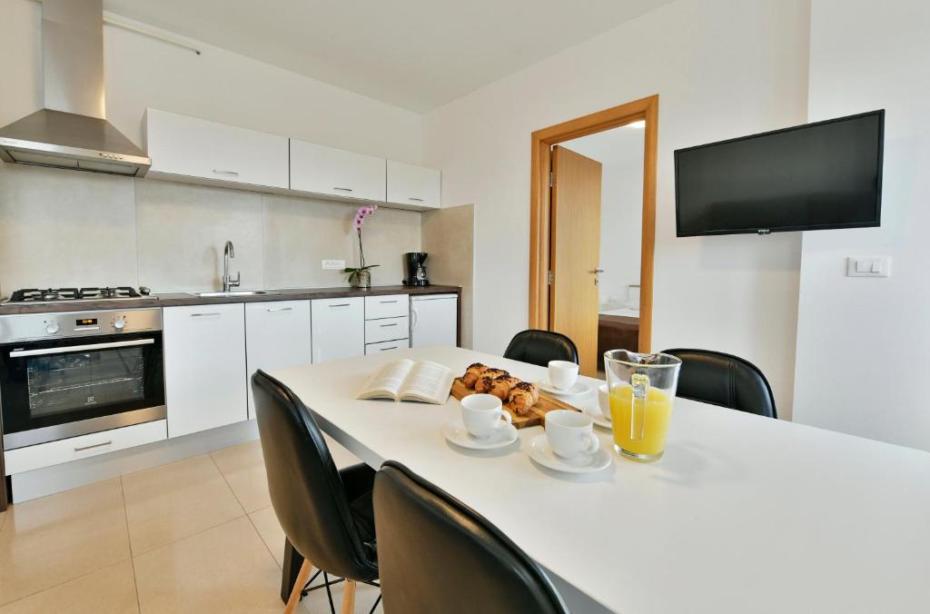 een keuken met een witte tafel met stoelen en drankjes erop bij Apart Residence Rudan 1 in Rovinj