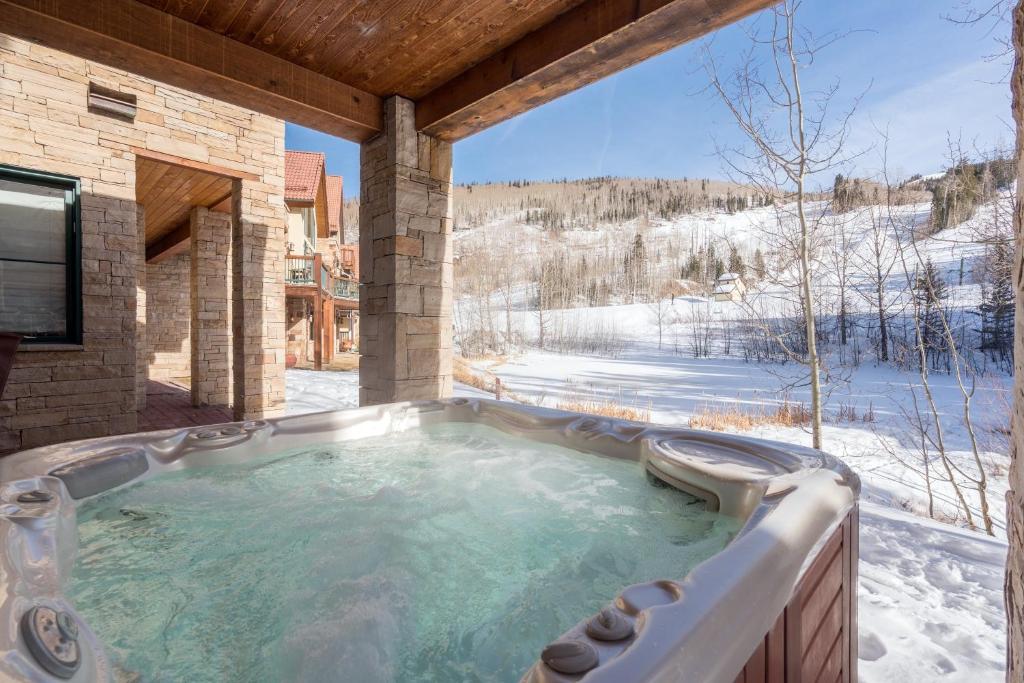 a jacuzzi tub on a deck with snow covered mountains at Telemark B by AvantStay Ski In Ski Out at the Heart of Mountain Village in Telluride