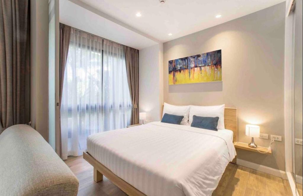 a bedroom with a large white bed and a window at Diamond Resort in Phuket Town