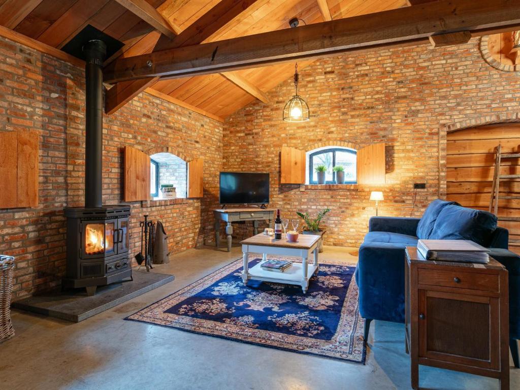 a brick walled living room with a couch and a fireplace at De Hoeve I in Hulsel