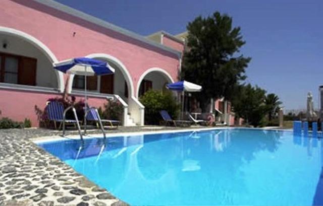 a person sitting in a chair next to a swimming pool at Villa Georgia in Perissa