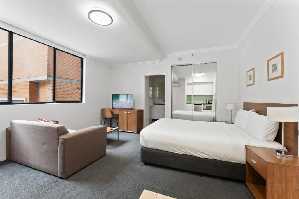 um quarto com uma cama, um sofá e uma televisão em APX Darling Harbour em Sidney
