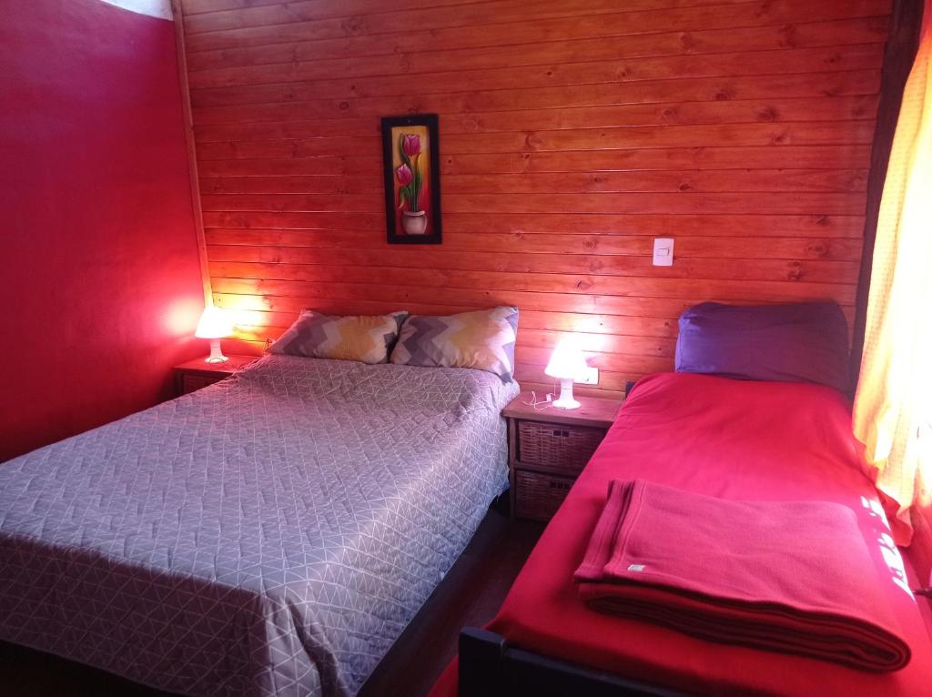 2 camas en una habitación con paredes rojas y 2 lámparas en Titernig del Monte en Capilla del Monte