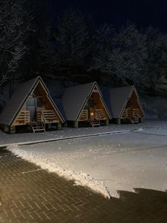 a row of wooden huts at night with snow at Căsuța - La Țanc in Martinie