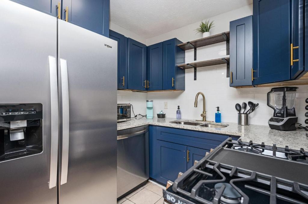 a kitchen with blue cabinets and a stainless steel refrigerator at Luxurious Extended Stay Dream~3 Kings~Desks~TV's in Snellville
