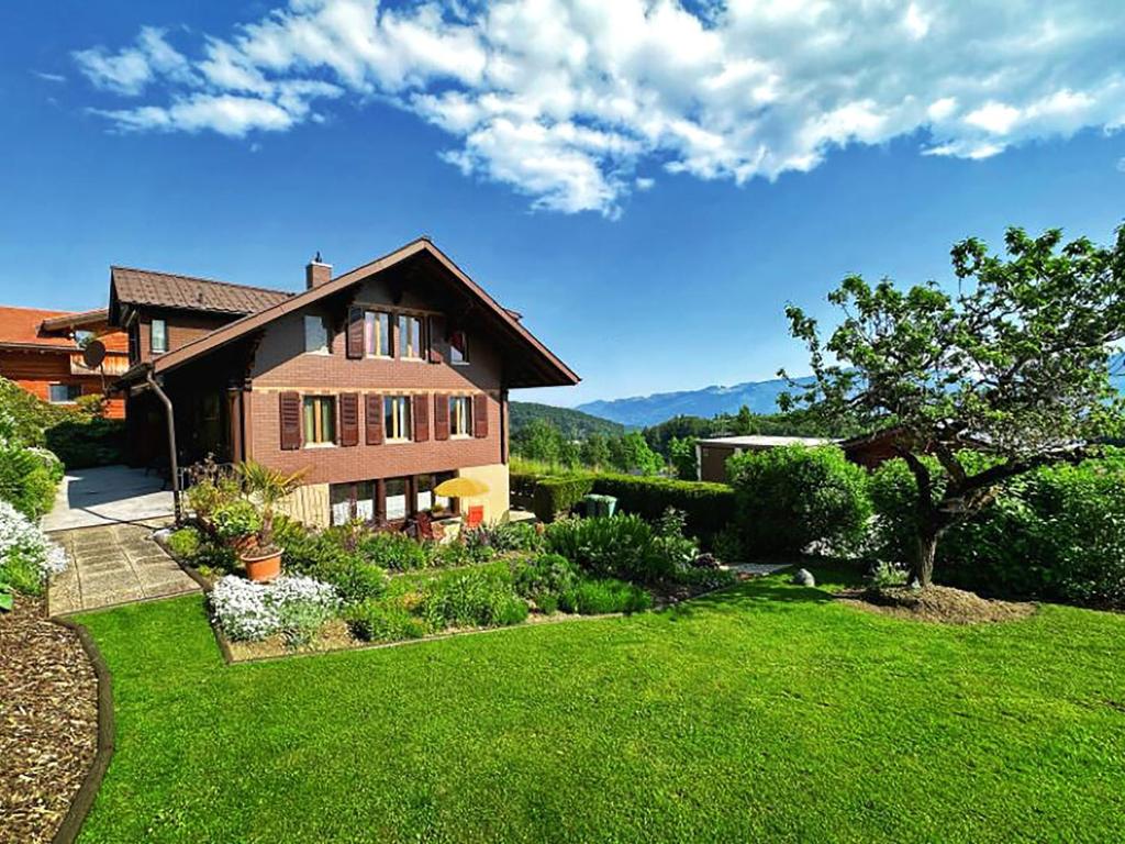 una casa con un patio con césped verde en Sunny Garden - Charmantes Chalet mit Aussicht, en Aeschi bei Spiez