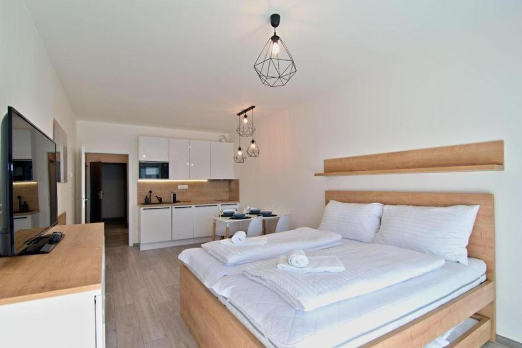 a bedroom with a large white bed and a kitchen at Apartment KORZO 318/3 in Lipno nad Vltavou