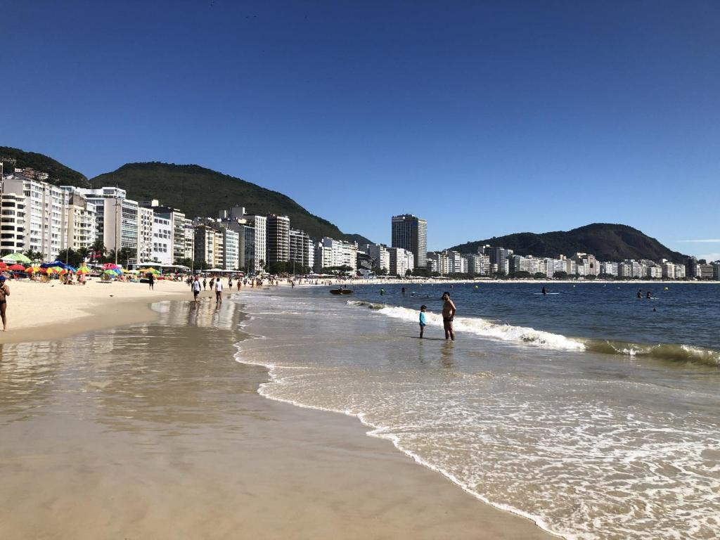 una playa con gente caminando por el agua y edificios en Posto 4- praia Copacabana 509, en Río de Janeiro