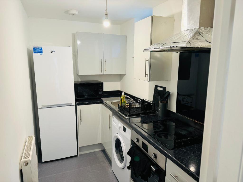 cocina con nevera blanca y lavadora en Town Centre Modern 1 Bed 1 Bath Apartment at Potter House by Lord Property en Aldershot