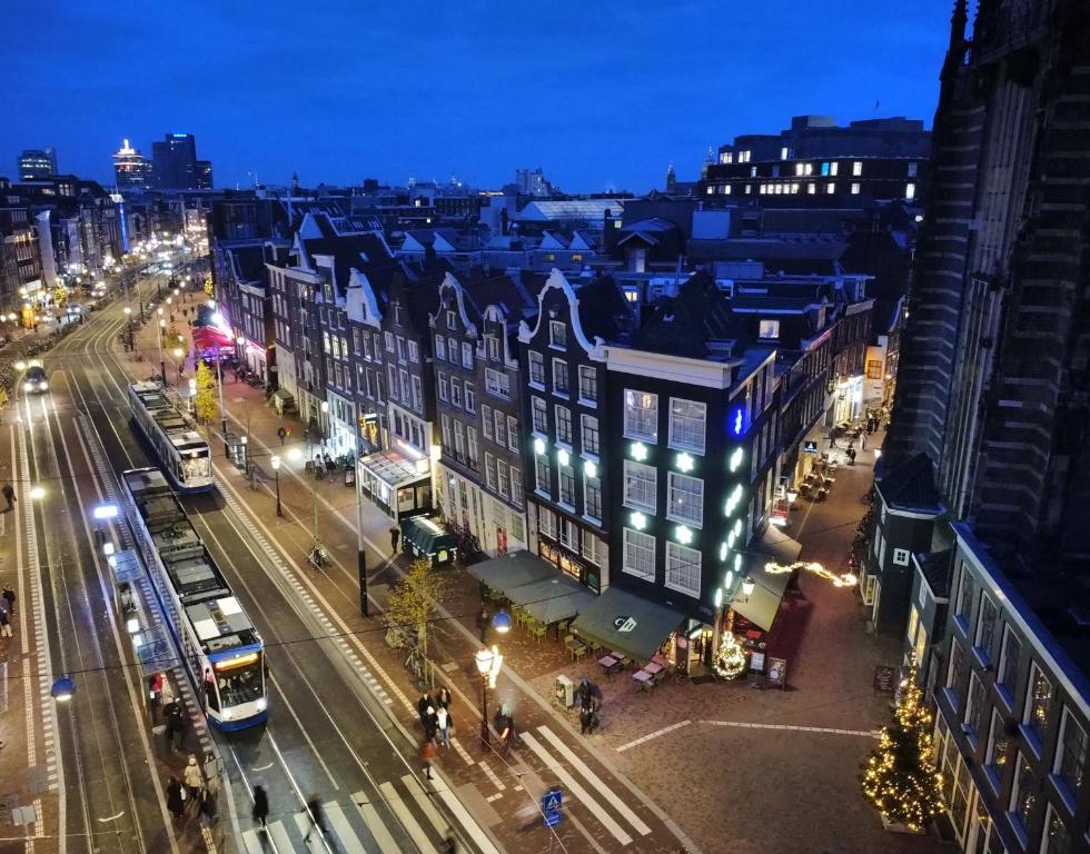 a city street at night with a bus at Hotel Corner House in Amsterdam