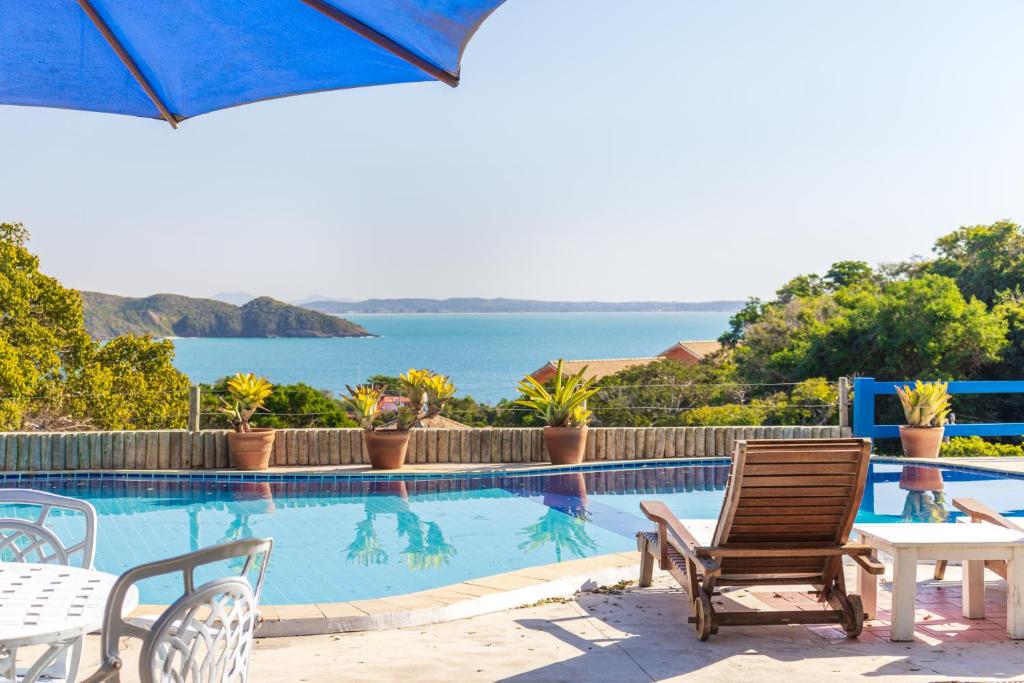 a swimming pool with chairs and a table and an umbrella at La Proeza Pousada in Búzios